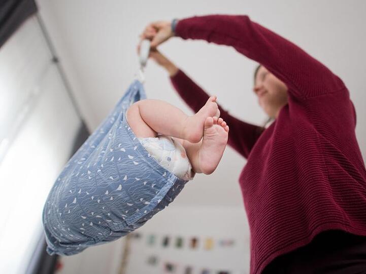 Ein Baby wird von einer Hebamme gewogen. Foto: Julian Stratenschulte/dpa/Archivbild
