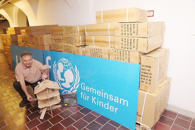 Albert Dietrich vor der Wagenladung von Spielen und Holzhäusern, die er für Unicef verkauft.