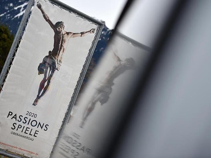 Ein Werbeplakat für die Passionsspiele 2020 spiegelt sich in einen Autofenster. Foto: Angelika Warmuth/Archivbild