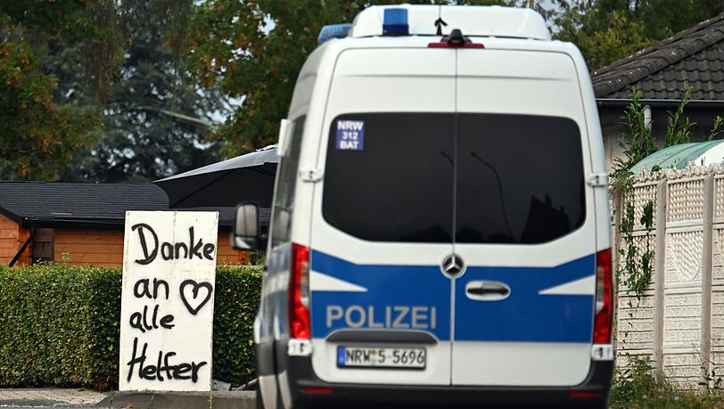 Ein Polizeifahrzeug f&auml;hrt an einem Schild mit der Aufschrift "Danke an alle Helfer" vorbei.