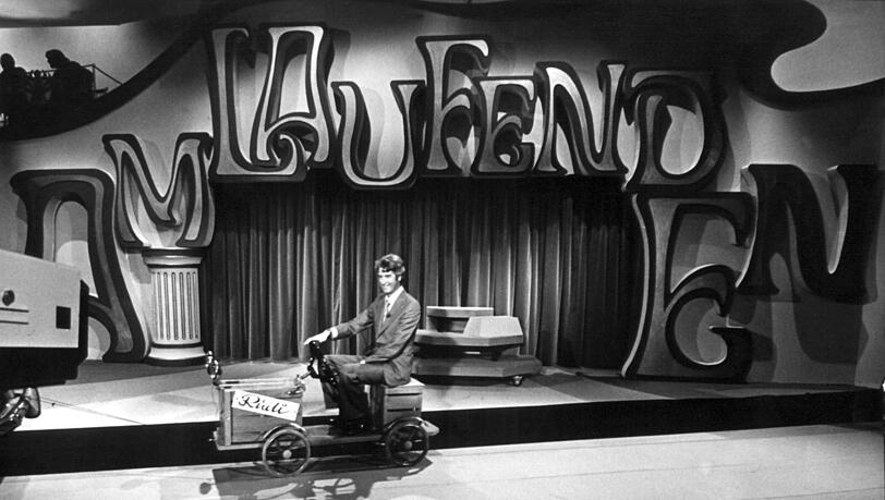 Moderator Rudi Carrel f&auml;hrt w&auml;hrend der Proben zu seiner Show "Am laufenden Band" mit einem Gef&auml;hrt durch das Fernsehstudio.