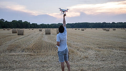 Aus der Ausstellung &bdquo;Freiraum 2030&ldquo;: Ein junger Mann spielt mit einem Quadrocopter auf einer Feldflur im Münchner Norden.