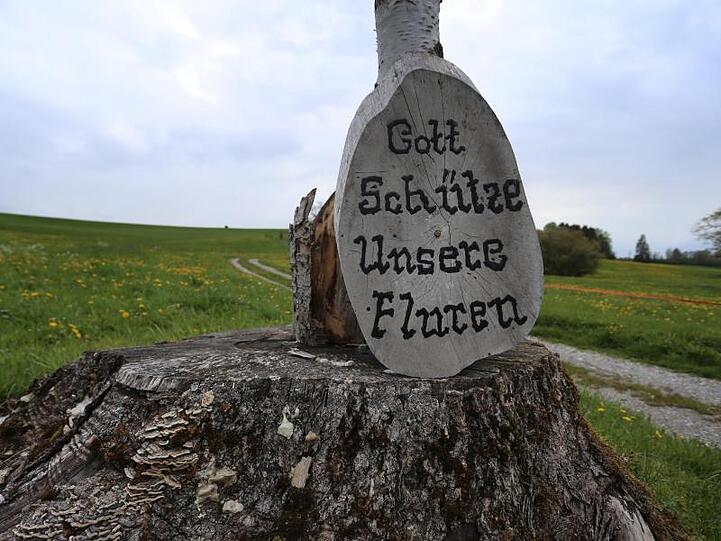 An einem Kreuz lehnt eine Holzscheibe mit der Aufschrift "Gott schütze unsere Fluren". Foto: Karl-Josef Hildenbrand/Archivbild