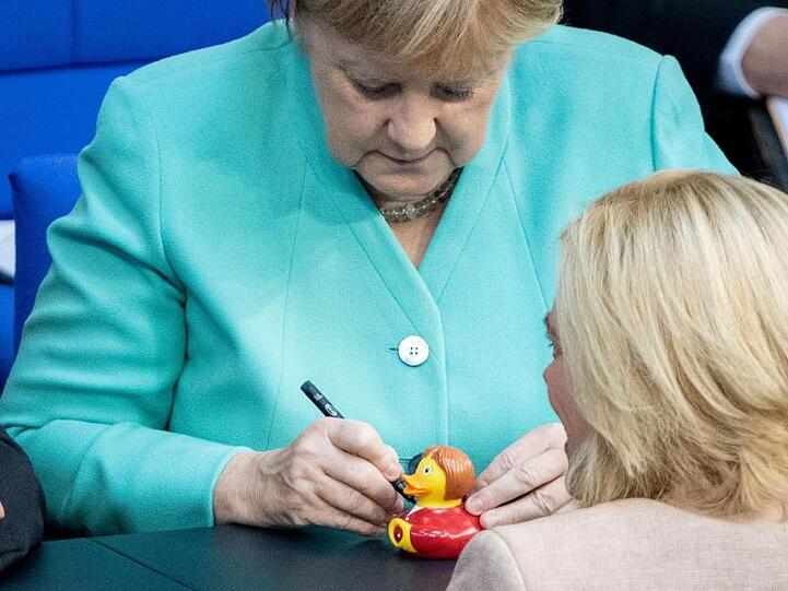 Bundeskanzlerin Angela Merkel signiert für Julia Klöckner eine Badeente.