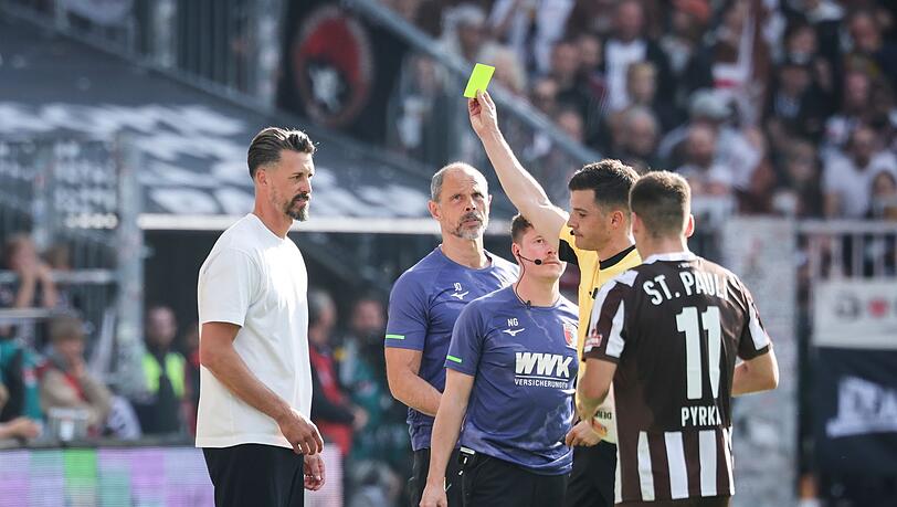 Schiedsrichter Harm Osmers zeigt Trainer Sandro Wagner (FC Augsburg, l) die gelbe Karte.