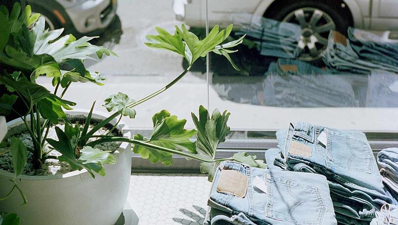 Jeans liegen gestapelt in einer Auslage. Fair Fashion als schonende Alternative.