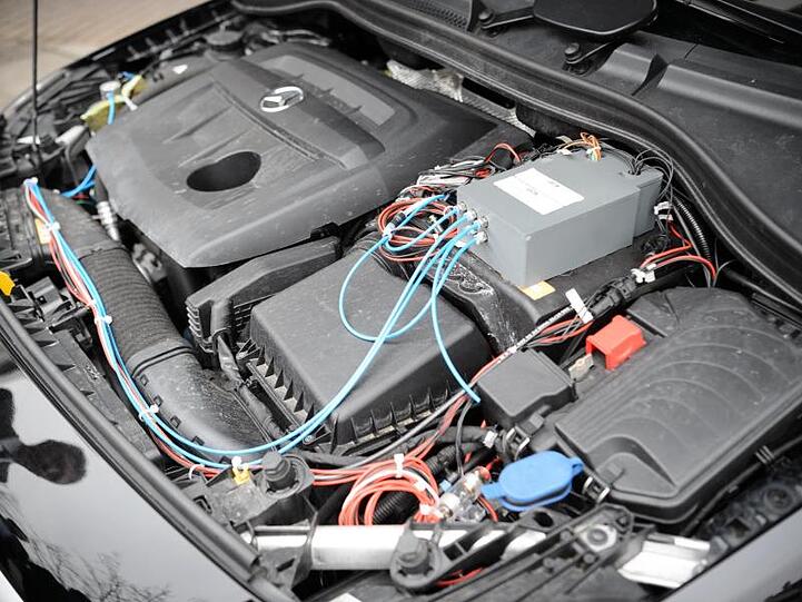 Im Motorraum eines Testfahrzeuges sind Bauteile zu sehen, die im Rahmen einer Umrüstung eingebaut wurden.