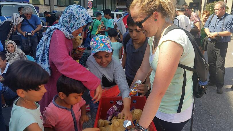 Freiwillige Helfer verteilen Kuscheltiere an die ankommenden Kinder
