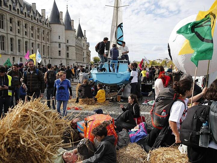 In Paris blockieren Aktivisten einen Verkehrsknotenpunkt in der Innenstadt. Rund um den Place du Châtelet nahe der Seine stellten sie Strohballen auf und setzten sich auf die Straße.