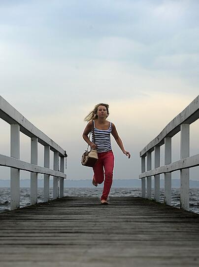 Eine junge Frau rennt am 20.06.2013 über einen Holzsteg am Zwischenahner Meer in Bad Zwischenahn zurück an Land und bringt sich vor einen aufziehenden Gewitter in Sicherheit.