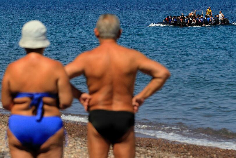 Krasser Gegensatz Gut genährte Urlauber aus Europa beobachten am 13. September auf der griechischen Insel Lesbos, wie ein maßlos überfülltes Schlauchboot mit syrischen Flüchtlingen auf die Küste zusteuert.