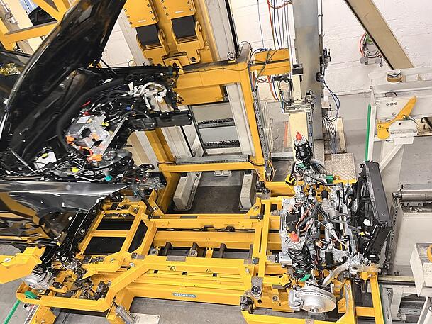 Die Hochzeit eines E-Autos: Das Fahrwerk und die Karosserie werden zusammengeführt. Anders als beim Verbrenner besteht die Antriebseinheit aus zwei Teilen. Die Hochzeit eines E-Autos: Das Fahrwerk und die Karosserie werden zusammengeführt. Anders als beim Verbrenner besteht die Antriebseinheit aus zwei Teilen.