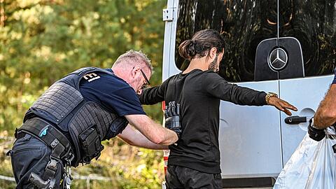 Ein Bundespolizist kontrolliert einen Migranten.