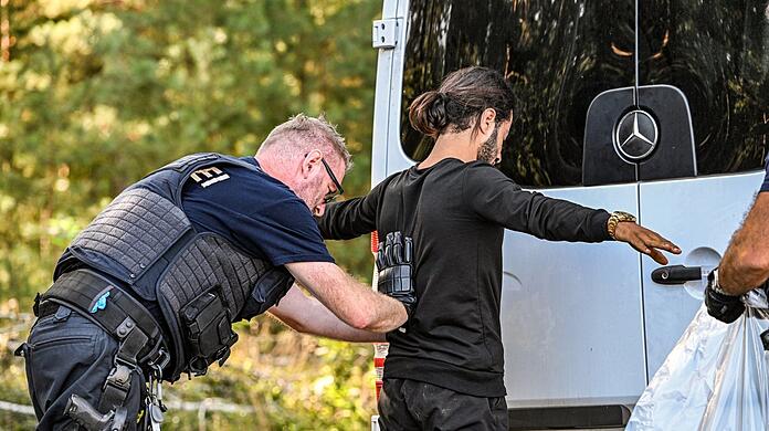 Ein Bundespolizist kontrolliert einen Migranten.
