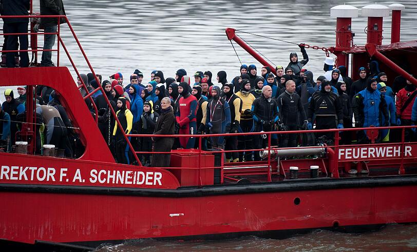 Die Teilnehmer sprangen von einem Feuerwehrboot aus in den Rhein, um mehrere hundert Meter flussabwaerts zu schwimmen.