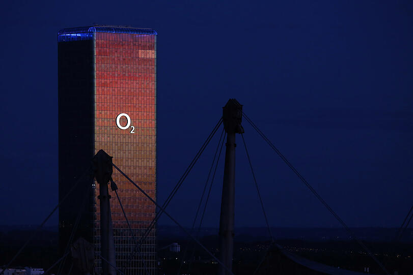 Das O2-Hochhaus reflektiert den rot leuchtenden Himmel vor dem Sonnenaufgang im Osten. Im Westen ist es noch fast Nacht.