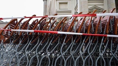 Auf dem Gendarmenmarkt in Berlin stehen zusammengestapelte Stühle hinter einem Absperrband.
