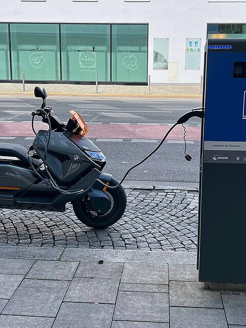 Eine E-Ladestation der Stadtwerke M&uuml;nchen. Ein E-Roller tankt gerade &Ouml;kostrom.