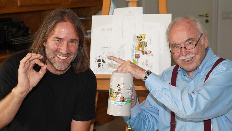 Liedermacher Roland Hefter (links) daheim bei AZ-Karikaturist Dieter Hanitzsch, der den Koa-Wiesn-Krug 2020 bemalt hat, aber den Fingerzeig gibt: Die Idee dazu hatte der umtriebige Sänger.