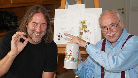 Liedermacher Roland Hefter (links) daheim bei AZ-Karikaturist Dieter Hanitzsch, der den Koa-Wiesn-Krug 2020 bemalt hat, aber den Fingerzeig gibt: Die Idee dazu hatte der umtriebige Sänger.