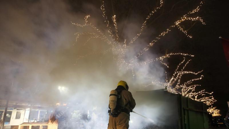 Krawalle in Rotterdam: Ein Feuerwehrmann löscht einen Container, der bei Protesten gegen die landesweite Ausgangssperre in Brand gesetzt wurde.