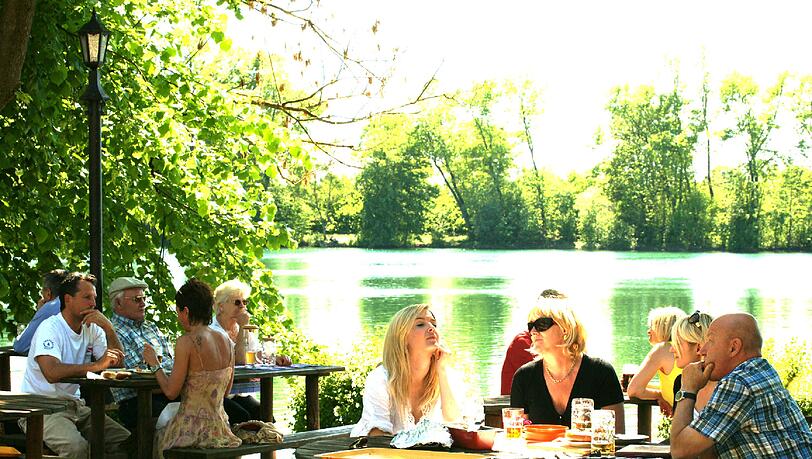 Und grünlich schimmert der See: Direkt am Wasser vom Langwieder sitzen die Gäste im Biergarten am Langwieder See. Und grünlich schimmert der See: Direkt am Wasser vom Langwieder sitzen die Gäste im Biergarten am Langwieder See.