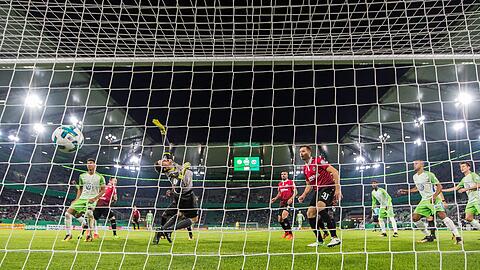 Wolfsburgs Ohis Felix Uduokhai trifft zum 1:0 in das Tor von Hannovers Torwart Michael Esser (M).
