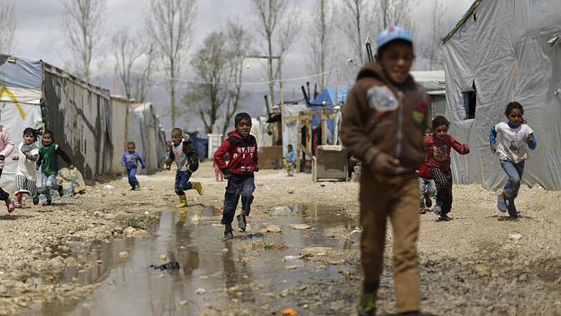 Syrische Kinder laufen durch eine Pfütze im Flüchtlingslager in Al-Marj im Libanon.
