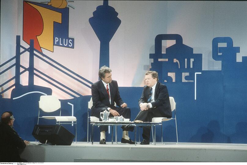 RTL startete als RTL plus am 2. Januar 1984. Wie inszenierte Moderator Rainer Holbe (l.) die Geburtsstunde?
a) Er entband als &bdquo;Arzt&ldquo; eine Frau von einem Fernsehgerät
b) Er war &bdquo;embedded Journalist&ldquo; im Hürther Kreißsaal
c) Er dankte Helmut Kohl für die &bdquo;Gnade der späten Geburt&ldquo;