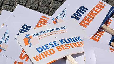 Plakate von Medizinern von bayerischen Unikliniken für einen Protestmarsch durch die Innenstadt liegen auf dem Boden.