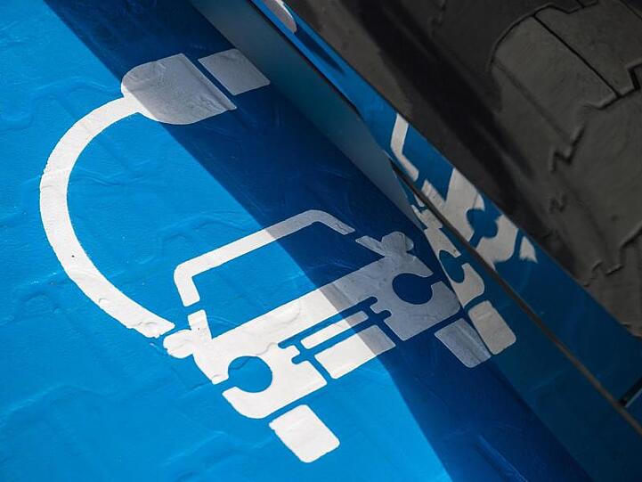 Ein Symbol für eine Ladestation auf einem Parkplatz.