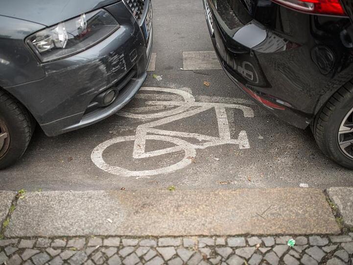 Geparkte Autos stehen auf einem Radweg.
