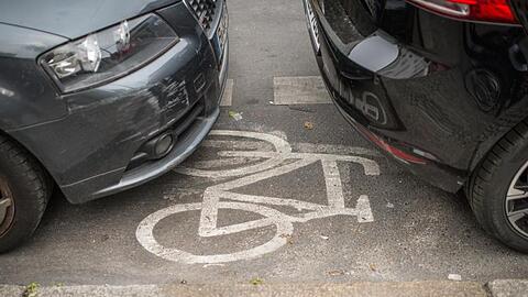 Geparkte Autos stehen auf einem Radweg.