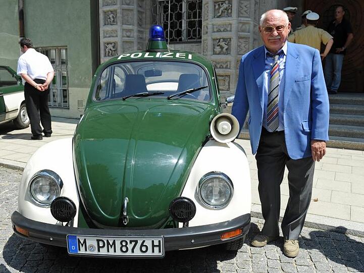 Rolf Schimpf steht 2013 vor dem Polizeipräsidium in München neben einem alten VW-Käfer-Polizeiauto. Foto: Andreas Gebert/dpa/Archivbild