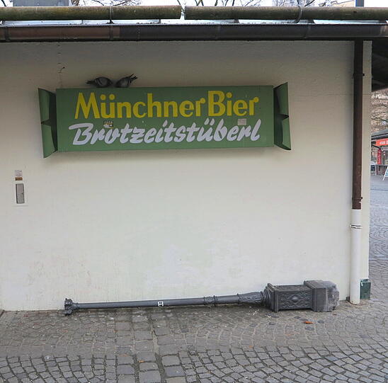 Neben dem Brotzeitstüberl liegt ein langer Mast.