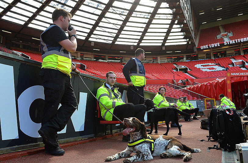 Leere Tribünen im Old-Trafford-Stadion von Manchester United. Sicherheitskräfte und Spürhunde sind im Einsatz.