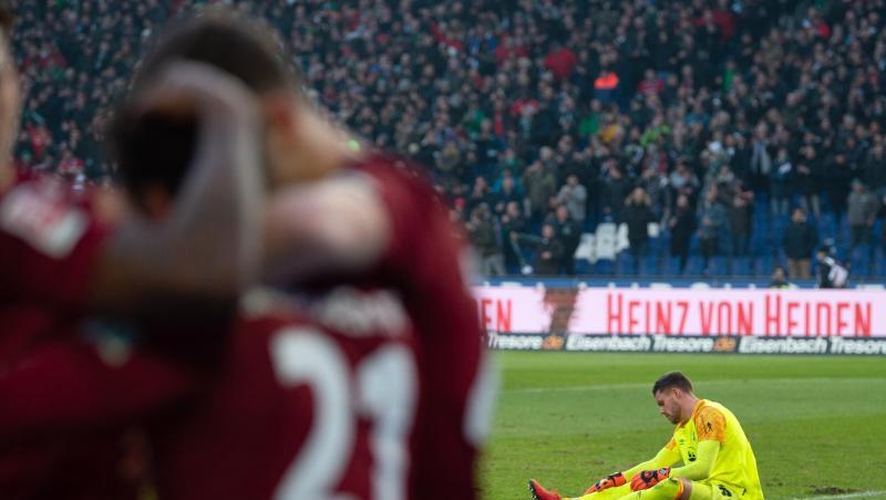 Nürnbergs Torwart Christian Mathenia sitzt am Boden, während Hannovers Spieler nach den 2:0 jubeln. Foto: Swen Pförtner