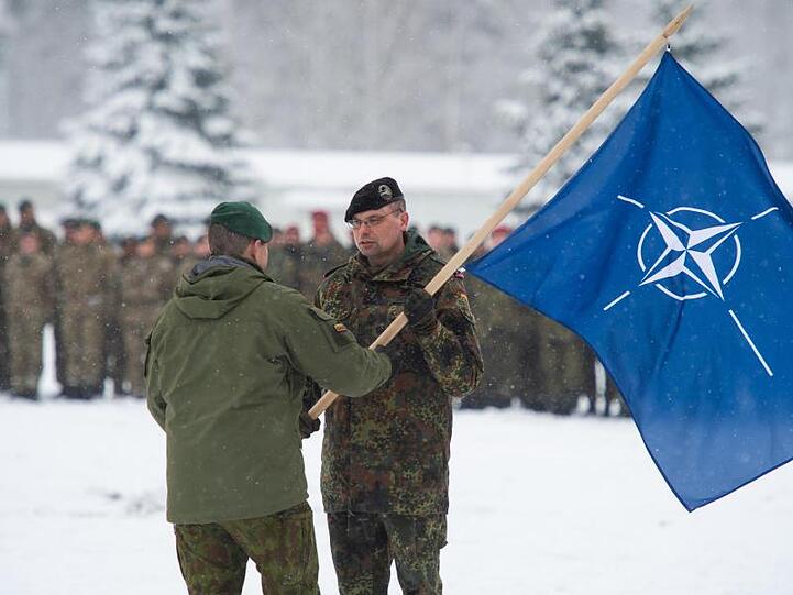 Der Brigadeführer von Iron Wolf, Steponauvicius Mindaugas, übergibt beim Übergabeappell die Natoflagge an Peter Papenbroock, Bundeswehr-Oberstleutnant und neuer Kommandeur der EFP Battlegroup in Litauen.