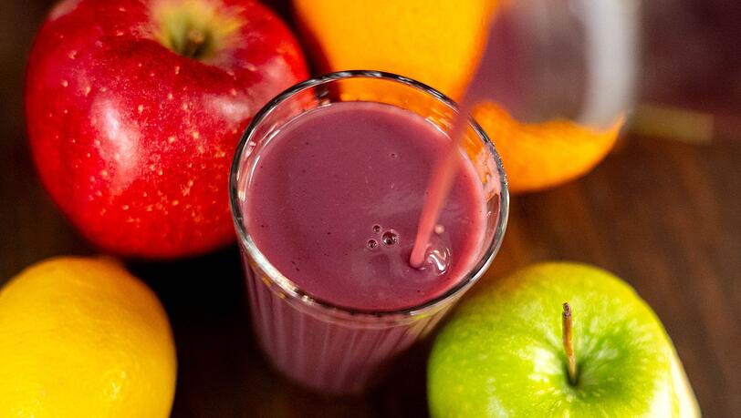 Jemand gießt roten Smoothie in ein Glas.