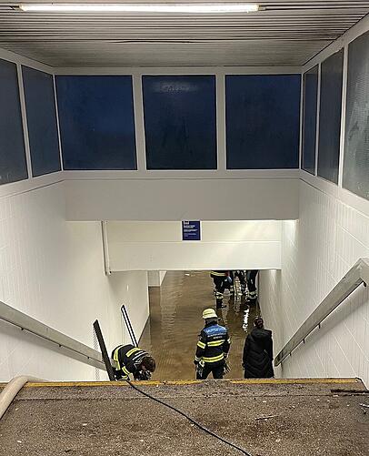 Einsatzkräfte der Berufsfeuerwehr München pumpen die vollgelaufenen Unterführung am S-Bahnhof Daglfing ab.