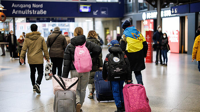 Eine ukrainische Familie wird von einem ukrainisch sprechenden Helfer (rechts) von einem Info-Point am Münchner Hauptbahnhof für geflüchtete Ukrainer zur Registrierung in einem Ankunftszentrum begleitet.
