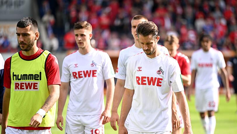 Die Kölner Spieler gehen nach der Niederlage in Heidenheim mit hängenden Köpfen vom Rasen.