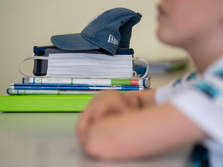 Eine Mund-Nasen-Bedeckung liegt während einer Unterrichtsstunde neben einem Schüler.