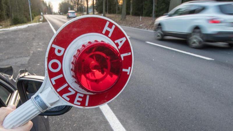 Ein Polizist hält eine Polizeikelle. Foto: Armin Weigel/Archiv