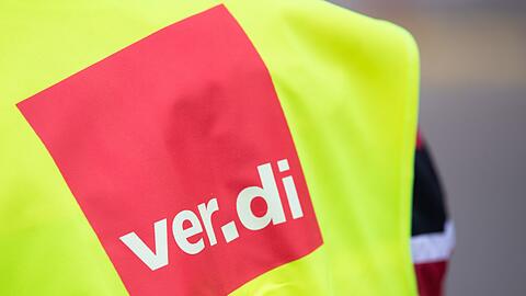 Ein Beschäftigter trägt bei einem Warnstreik eine Warnweste von Verdi.