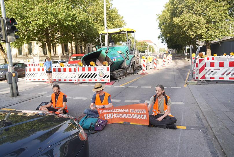Mehrere Menschen kleben sich am Donnerstagmorgen in München auf die Straße.