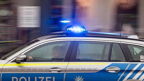 Ein Fahrzeug der bayerischen Polizei fährt mit Blaulicht durch die Innenstadt.