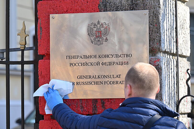 Ein Mitarbeiter reinigt das Schild des russischen Generalkonsulats. Unbekannte hatten den Eingang mit roter Farbe beschmiert.