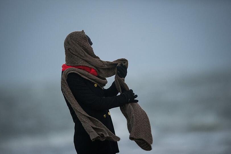 Eine Frau steht mit wehendem Schal am 06.12.2013 auf der nordfriesischen Hallig Langeneß