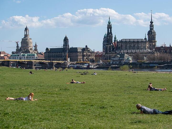 Menschen liegen auf den Elbwiesen in Dresden.